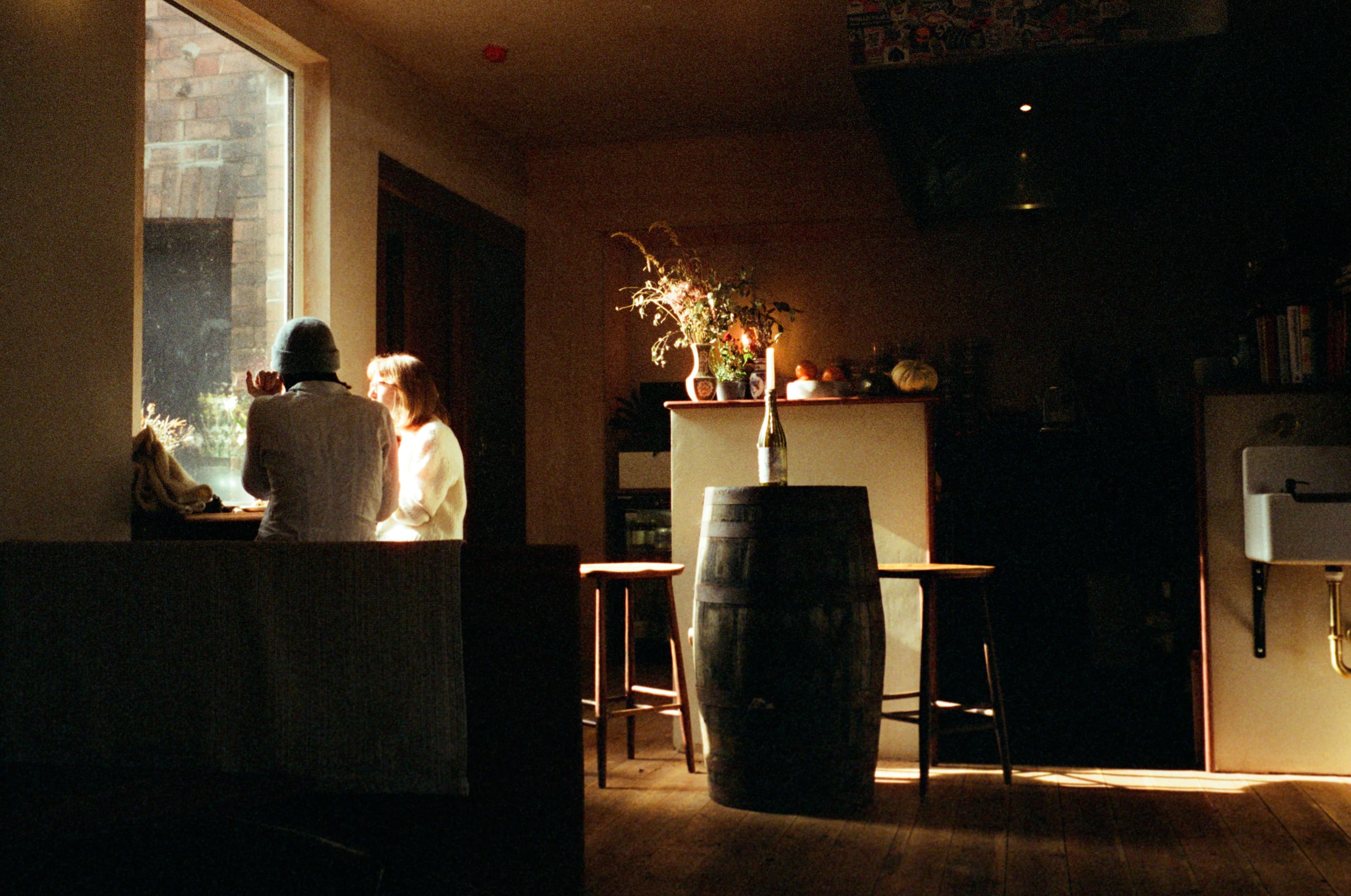 Two people sitting in a quiet bar beside a bright window.